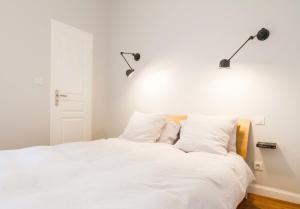 图卢兹Les Loges des Chalets的卧室配有白色床,墙上有两盏灯