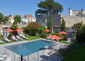 诺亚芒提亚Le Général d'Elbée Hotel & Spa - Teritoria的一个带红色遮阳伞和椅子的游泳池