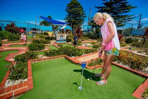 仙女港BIG4 Port Fairy Holiday Park的女人在花园里打高尔夫球