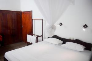 希克杜沃My Place Hikkaduwa的一间卧室配有一张带白色床单和镜子的床