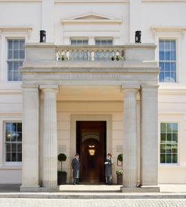 伦敦The Lanesborough, Oetker Collection的两个人站在白色建筑的入口处