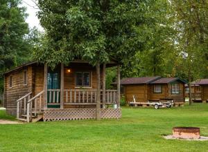 弗里蒙特Fremont RV Campground Cottage 28的小木屋设有门廊和树