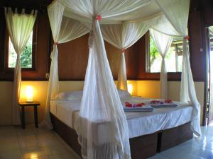 布纳肯布纳肯恰恰自然度假酒店的卧室配有带白色窗帘的天蓬床