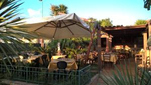 夸尔图-圣埃莱娜La Fontanella的室外餐厅设有桌子和遮阳伞