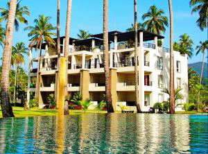 象岛象岛诺伊乐园公寓的水体前有棕榈树的建筑
