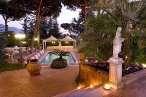 格罗塔费拉塔维拉费拉塔公园酒店的花园设有游泳池、桌子和喷泉