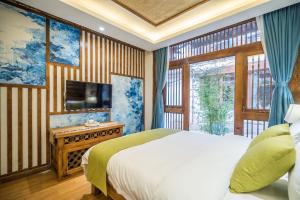 丽江丽江悦途精品度假酒店的一间卧室设有一张床、一台电视和一个窗口。