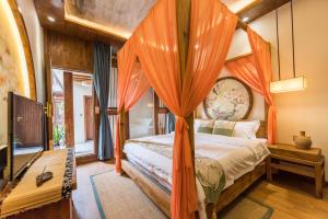丽江丽江悦途精品度假酒店的一间卧室配有带橙色窗帘的天蓬床