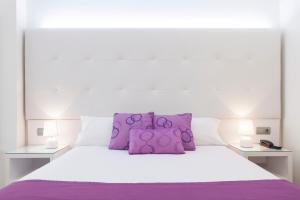 阿利坎特阿利坎特阿巴西亚酒店的白色的床,上面有紫色枕头