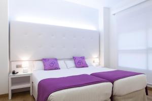 阿利坎特阿利坎特阿巴西亚酒店的卧室配有一张带紫色枕头的大型白色床。
