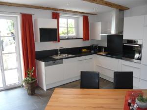 散特Chasa Vidos 270 - Familie Scandella的厨房配有白色橱柜、红色窗帘和桌子