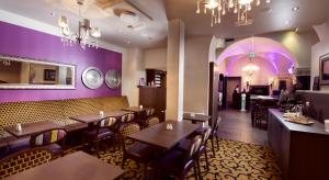 海宁格松Banken Hotel的餐厅拥有紫色的墙壁和木桌及椅子