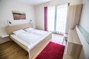 SzárÖregtölgy Vendégház的卧室配有白色的床和红色地毯。