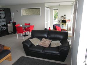 纳尔逊Beach side Apartment Nelson的客厅配有黑色真皮沙发和红色椅子