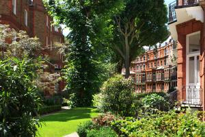 伦敦The Franklin London - Starhotels Collezione的一座花园,花园内种植了灌木和树木,并建有建筑物