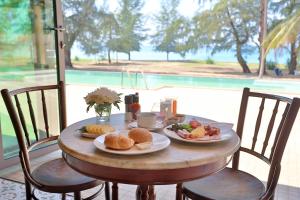 迈考海滩Coriacea Beachfront Boutique Phuket Resort - SHA Plus的一张木桌,上面放着两盘食物