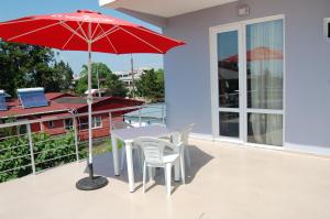 科布列季Hotel Niniko的阳台的红色遮阳伞,配有桌椅