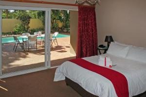 德班Durban Manor Guest House的一间卧室配有一张床,庭院配有桌子