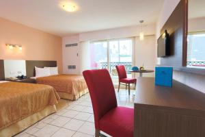 巴亚尔塔港Crown Paradise Club All Inclusive的酒店客房,设有两张床和一张红色椅子