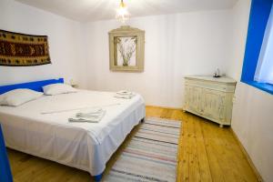 茹里洛夫卡La Lipoveni的卧室配有白色的床和梳妆台。
