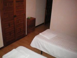 San ViteroHotel Rural Los Perales的小房间设有两张床和一扇门
