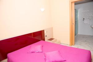 AdorAlojamento turistico Perla的粉红色的床,上面有两个粉红色的枕头