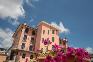 圣乔瓦尼·罗通多里昂酒店及罗索卡瓦利诺餐厅的粉红色的建筑,前面有紫色的花