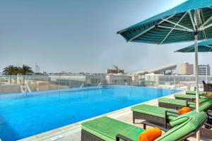 迪拜奥酷瑞中庭酒店的一座大楼内的游泳池,配有椅子和遮阳伞