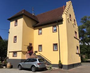 莱茵河畔威尔阿尔特斯沃特豪斯旅馆的前面有一个黄色教堂,有车停在