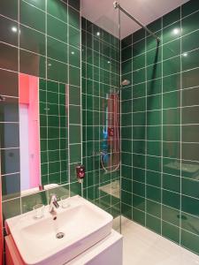 美因河畔法兰克福大使酒店的绿色瓷砖浴室设有水槽和淋浴