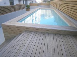 巴约讷Apartamentos Ababides Playa的铺有木地板的甲板上的游泳池