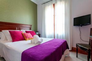 塞维利亚巴克酒店的一间卧室配有一张大床和紫色毯子