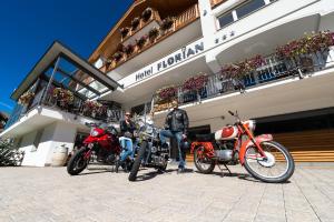 塞尔瓦迪加尔代纳山谷Hotel Florian的两个骑摩托车的人停在大楼前