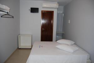 特林达迪Pousada Santana - Trindade Goiás的卧室配有白色床和2个白色枕头
