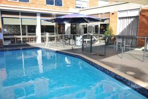 悉尼北岸普特希尔酒店的一个带遮阳伞和桌椅的游泳池