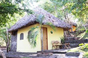 La LagunaSan Simian Lodge的小屋拥有茅草屋顶,是一座黄色的小小屋