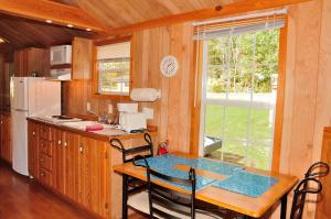 Elkhart LakePlymouth Rock Camping Resort Deluxe Cabin 16的厨房配有桌椅和窗户。