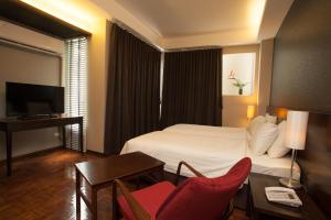 曼谷班西隆第3巷酒店的酒店客房带一张床、一张桌子和椅子