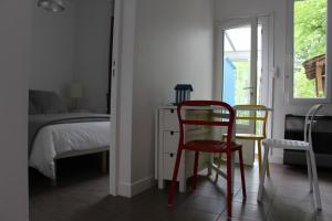 La RicheLa Garzette的一间卧室配有一张床、一张红色椅子和一张书桌