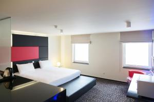 拉卢维耶尔三星酒店的一间卧室配有一张床、一张书桌和两个窗户。