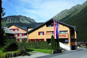 布雷根茨沃尔德地区奥Alpen Hotel Post的大楼前有旗帜的酒店