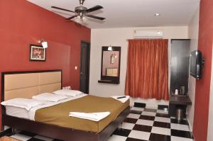 马杜赖Sri ArulMuthu Residency的一间卧室配有一张红色墙壁的床和 ⁇ 格地板