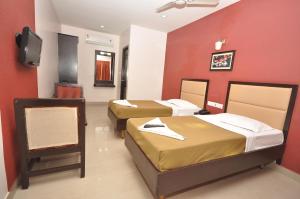 马杜赖Sri ArulMuthu Residency的一间酒店客房,设有三张床和一台平面电视