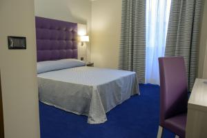 都灵都灵港苏萨酒店的一间卧室配有一张大床和紫色床头板