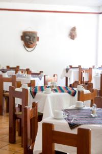 帕伦克Hotel Maya Palenque的餐厅设有桌椅和墙上的面具