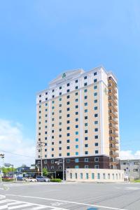 常滑市Spring Sunny Hotel Nagoya Tokoname ekimae的前面有一条街道的白色大建筑