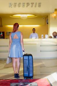 赛比什Hotel FAN Sebes的一位在商店里拿着手提箱站着的女人