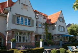 德哈恩Romantik B&B Zonnehuis的白色的大房子,设有蓝色的窗户