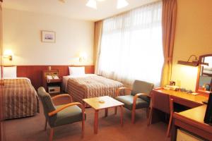 Ichikikushikino串木野艾克西亚酒店的酒店客房带一张床、一张桌子和椅子