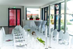 Gnoien格诺因梅克伦堡酒店霍夫格酒店的一张白色长桌,配有白色椅子和桌子及盘子